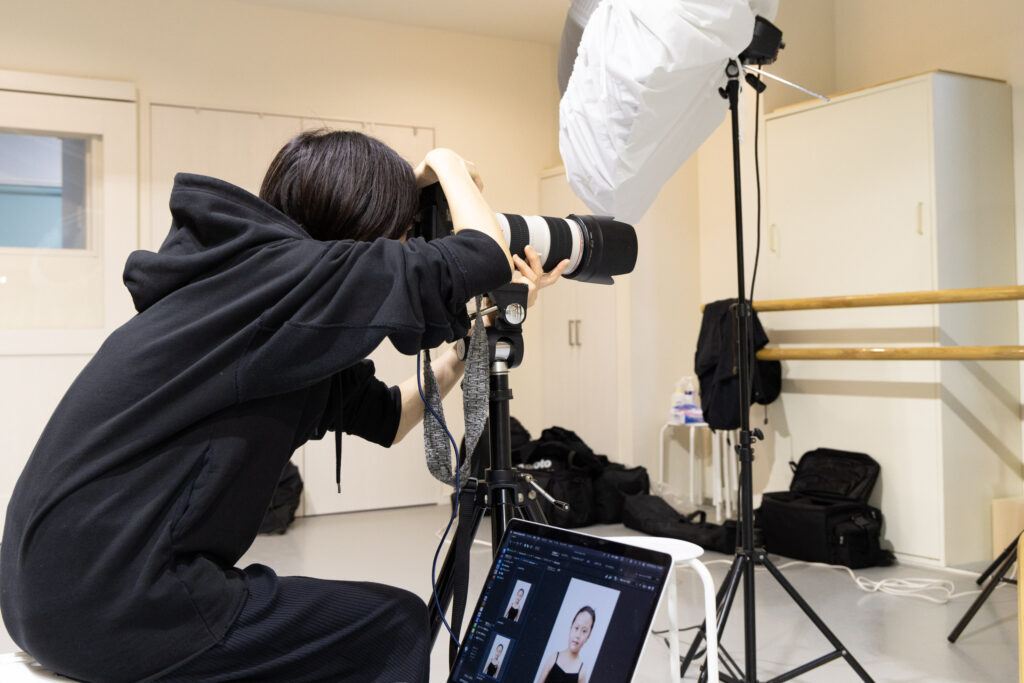 バレエ教室のスタジオで生徒のプログラム用顔写真の撮影をするカメラマン