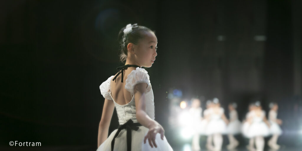 バレエ発表会の舞台袖で本番の出番を待つ小さなバレリーナの写真